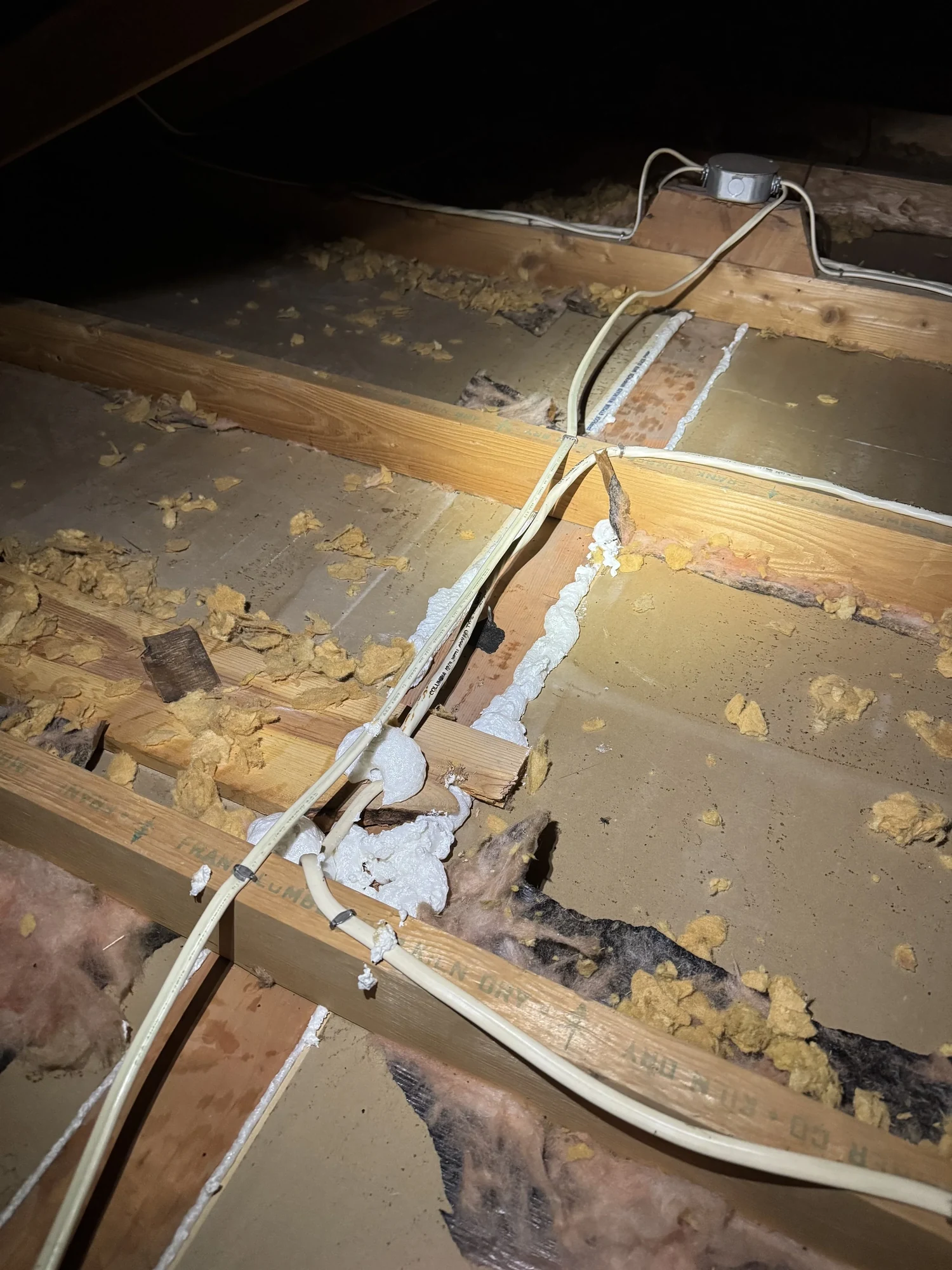 Beads of foam sealant along attic top plates and around wiring