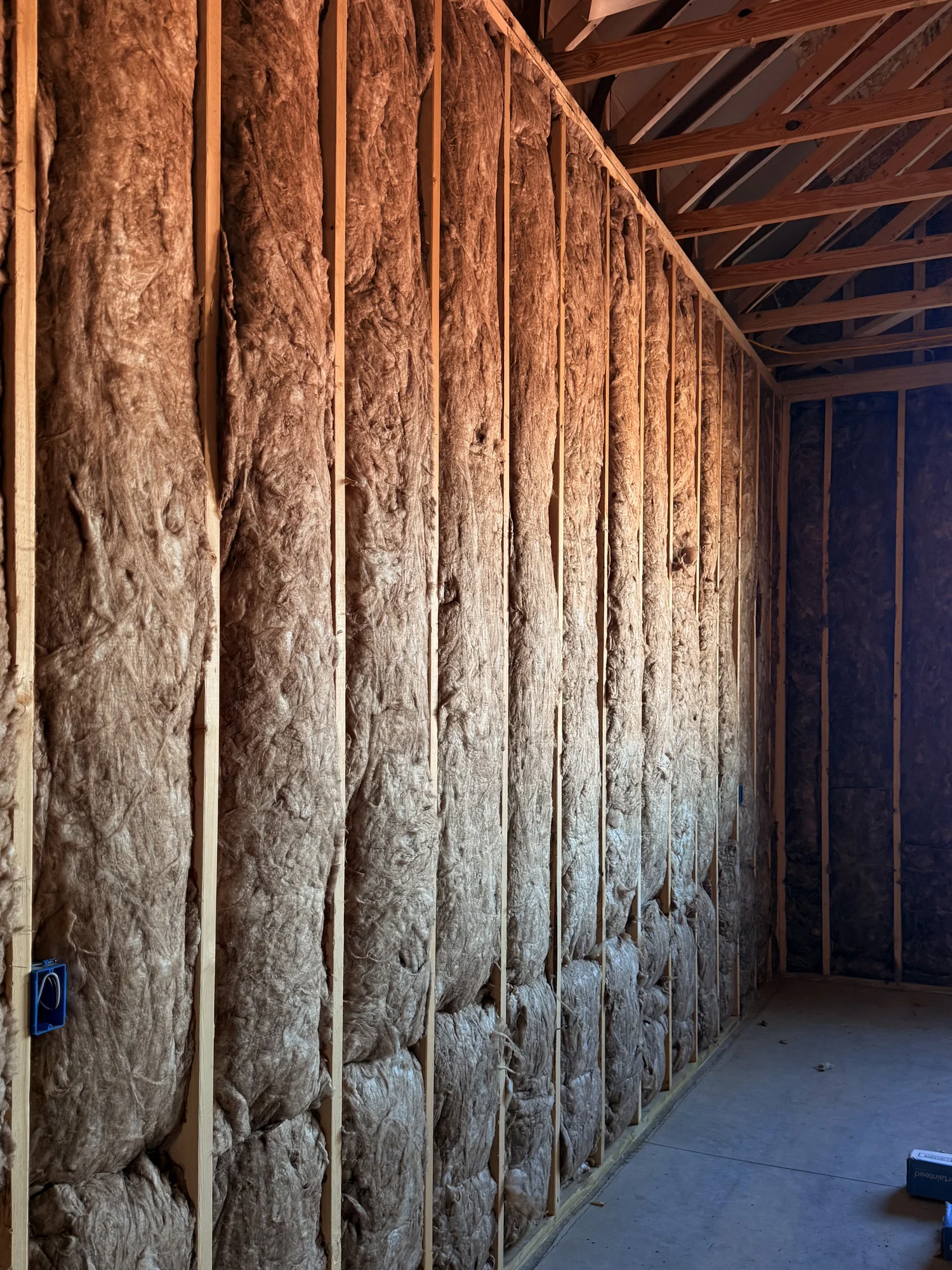 Batt insulation fitted between the studs of a framed wall