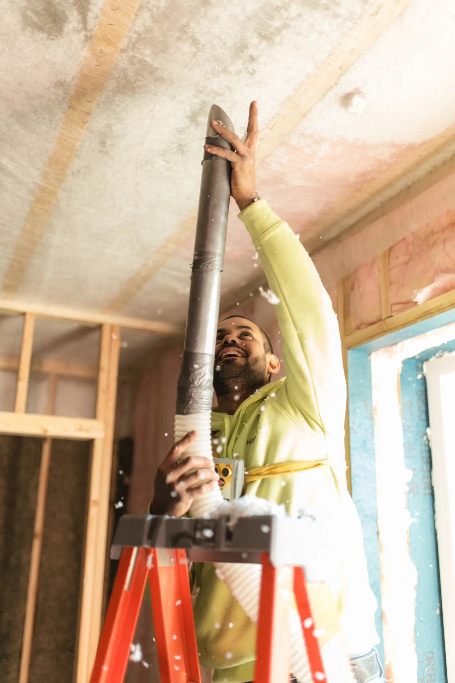 Installer looking up as he feeds the blowing hose into a netted ceiling