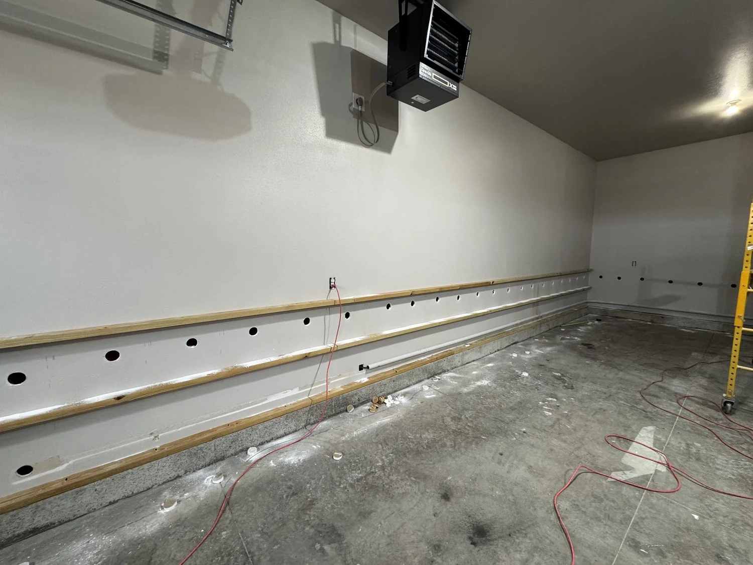 Finished garage wall with two rows of access openings between wood strips, low on the wall
