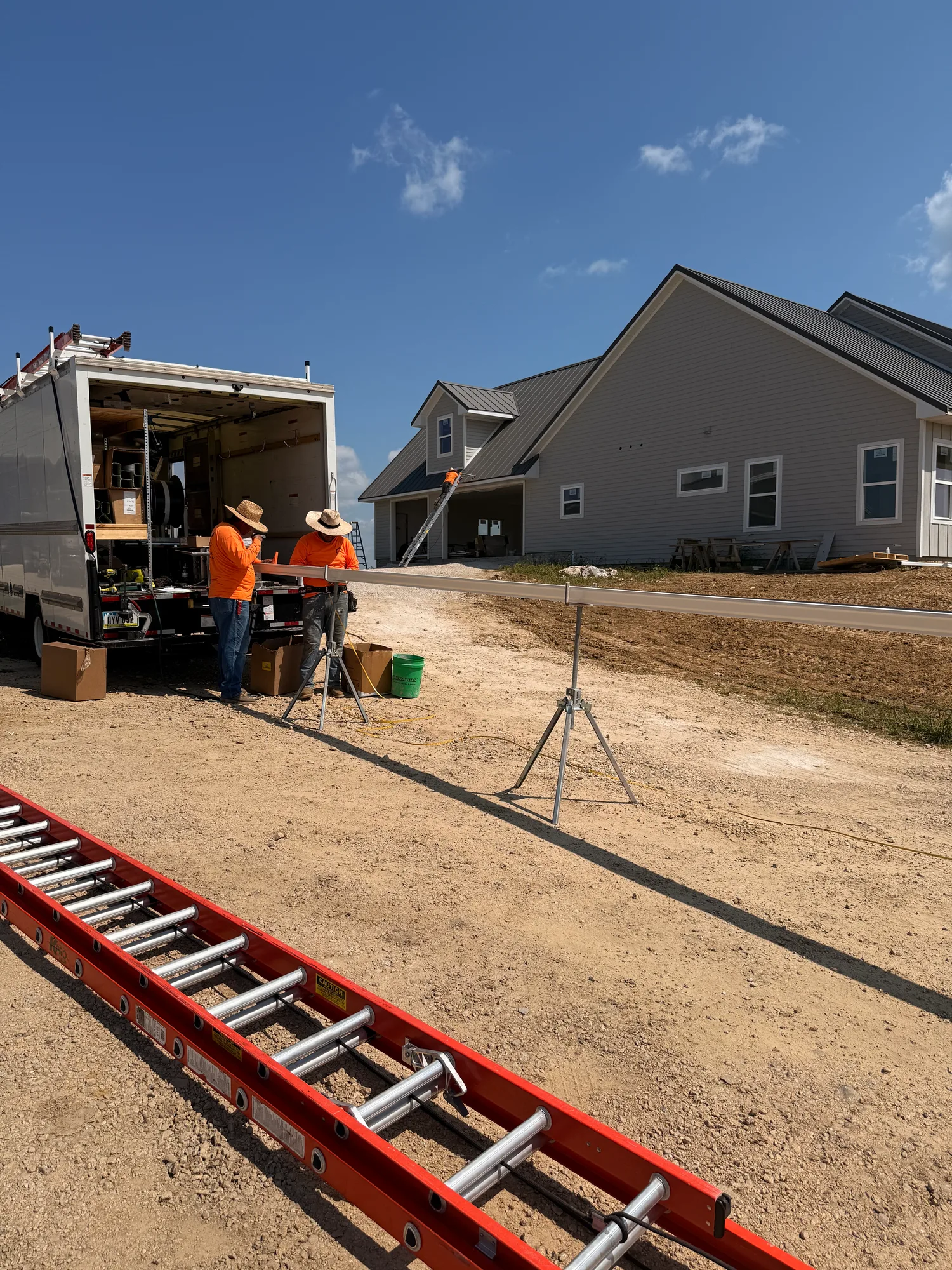 Two Thermal Shop gutter installers at their trailer beside a newly built home