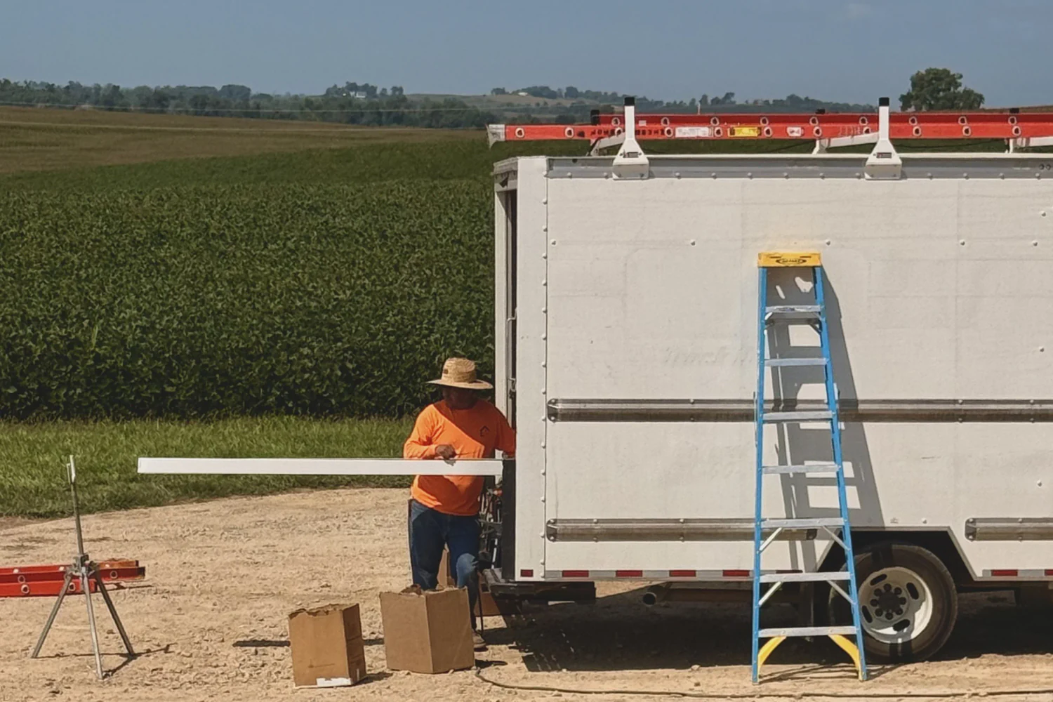 Installer feeding a new gutter run off the forming machine at the back of the gutter trailer