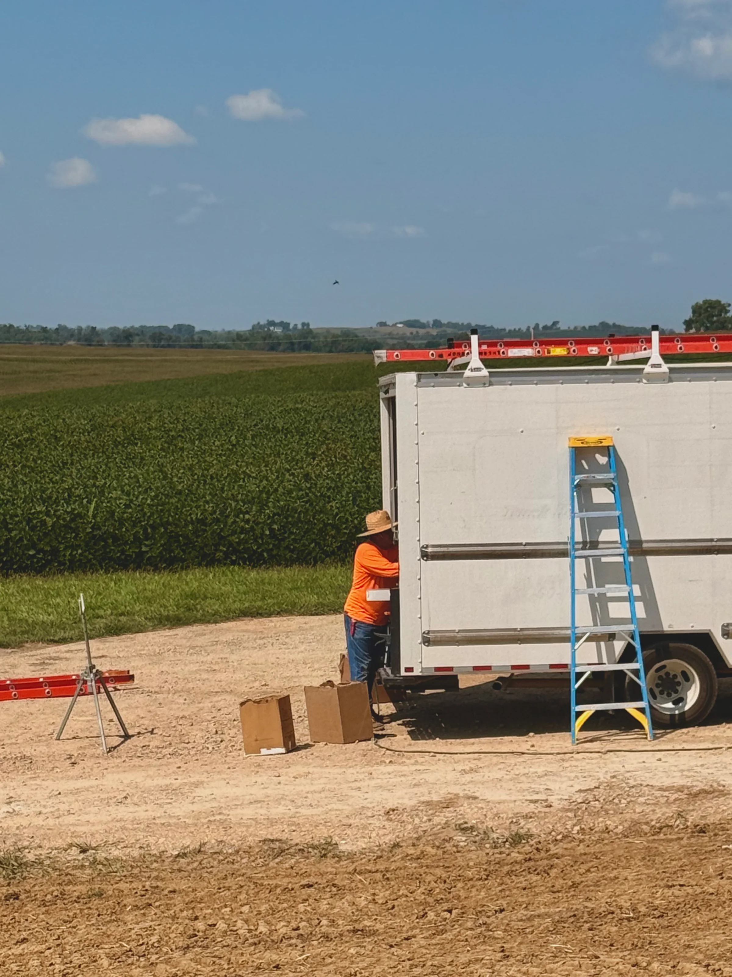 The first length of white gutter emerging from the machine in the side of the box truck as the installer steadies it