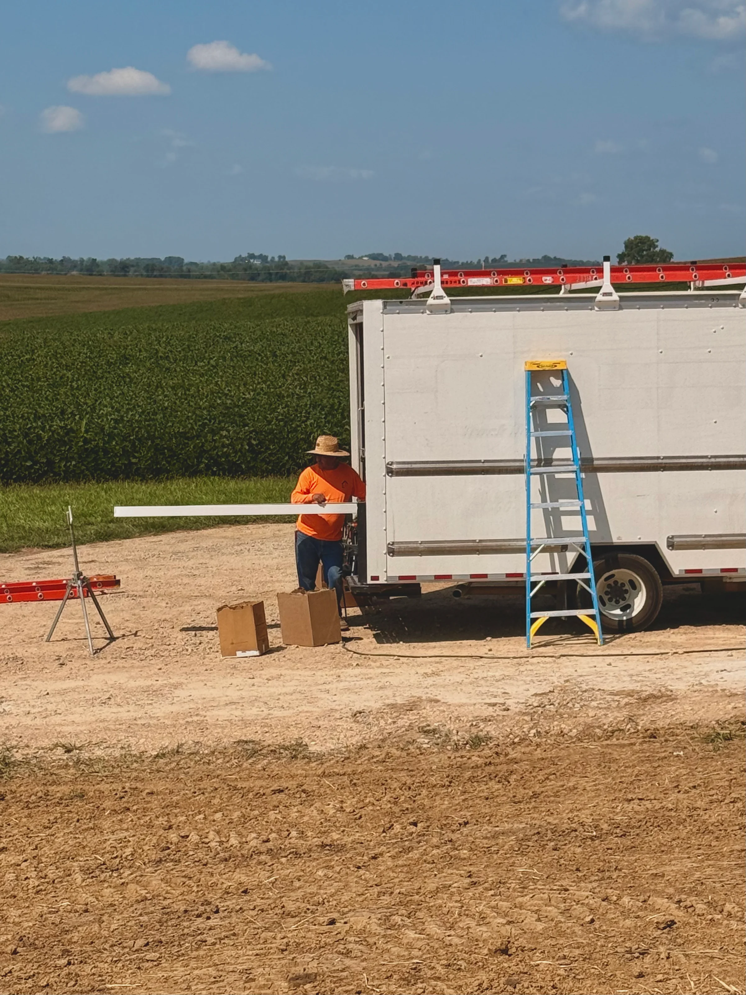 A seamless white gutter several metres long running out of the side of the box truck, held level by the installer