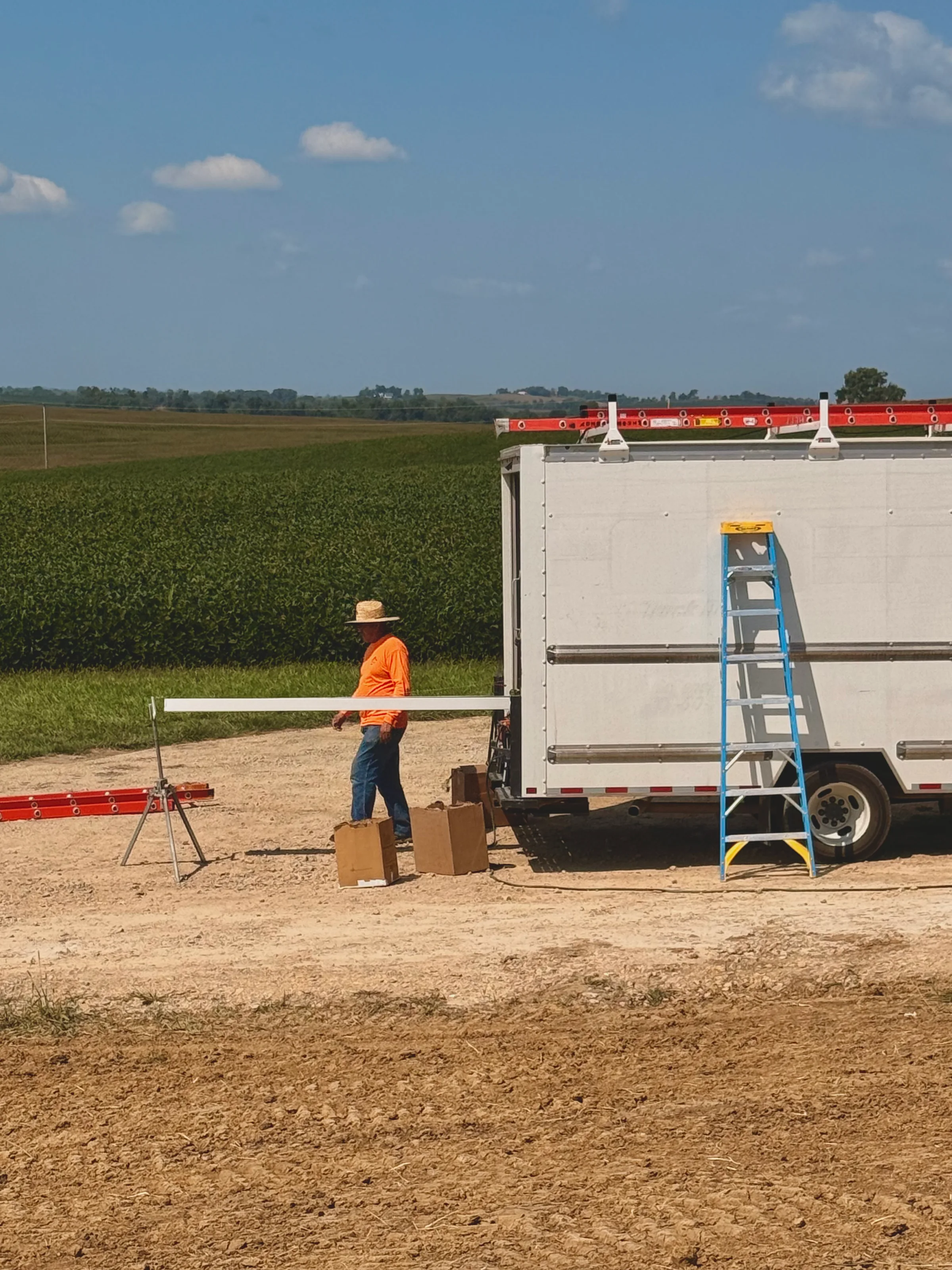 The installer walking the finished gutter length away from the truck toward the roller stand set up on the gravel