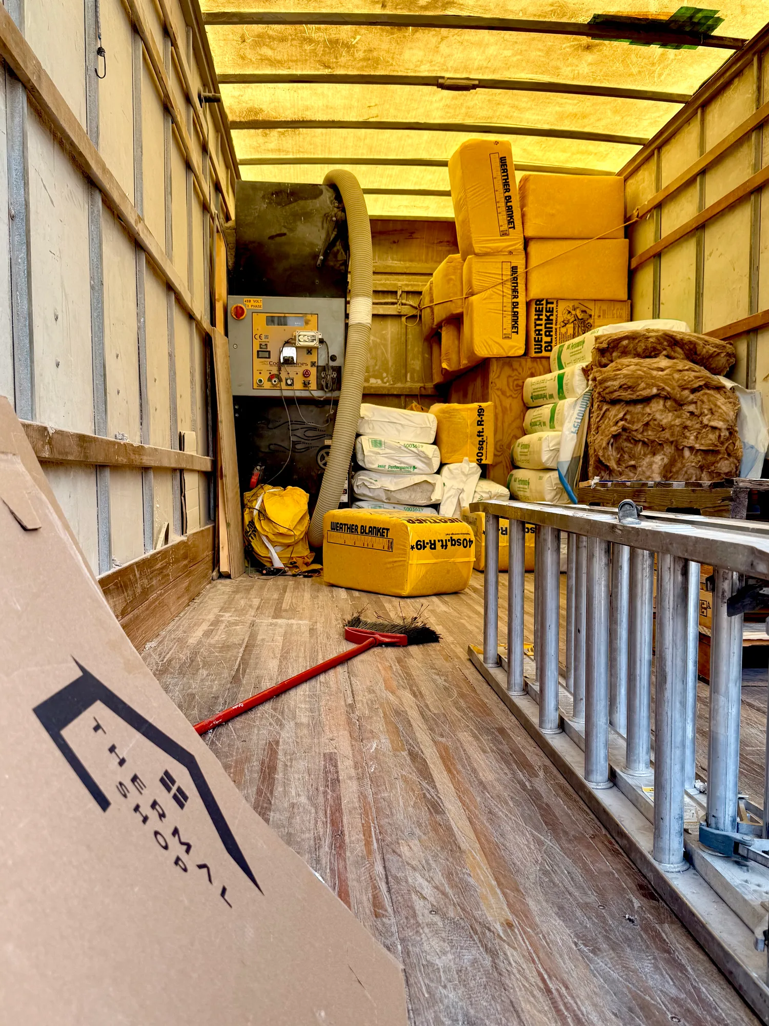 Inside a Thermal Shop insulation truck: the blowing machine, hose, and stacked bags