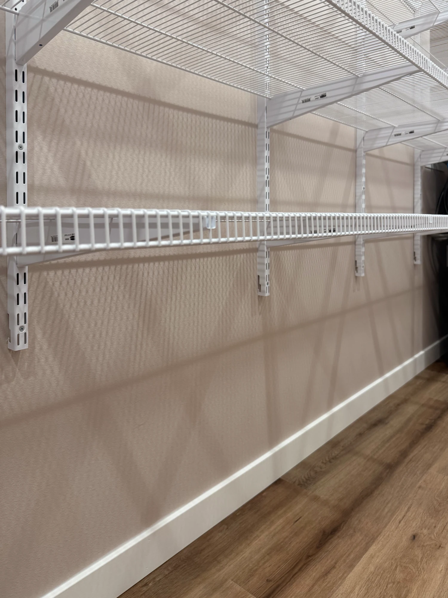 White wire shelves on brackets hung from slotted steel standards along a wall