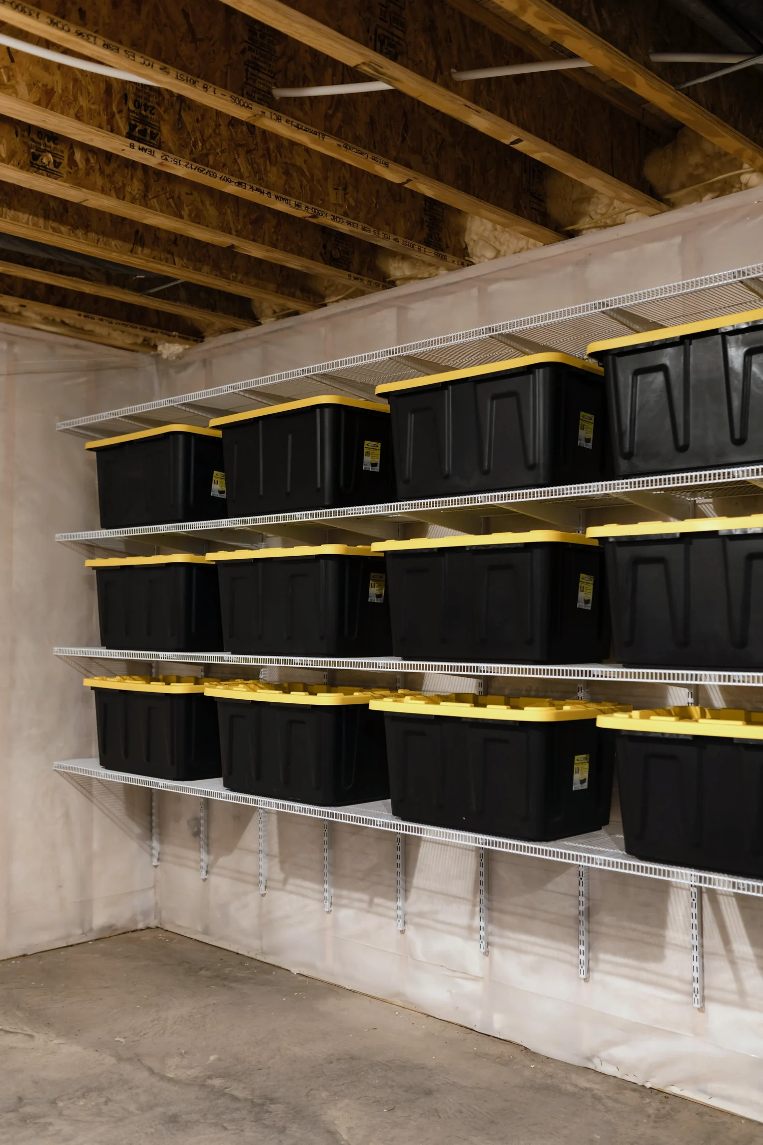 Storage bins on white wire shelves in the corner of a basement