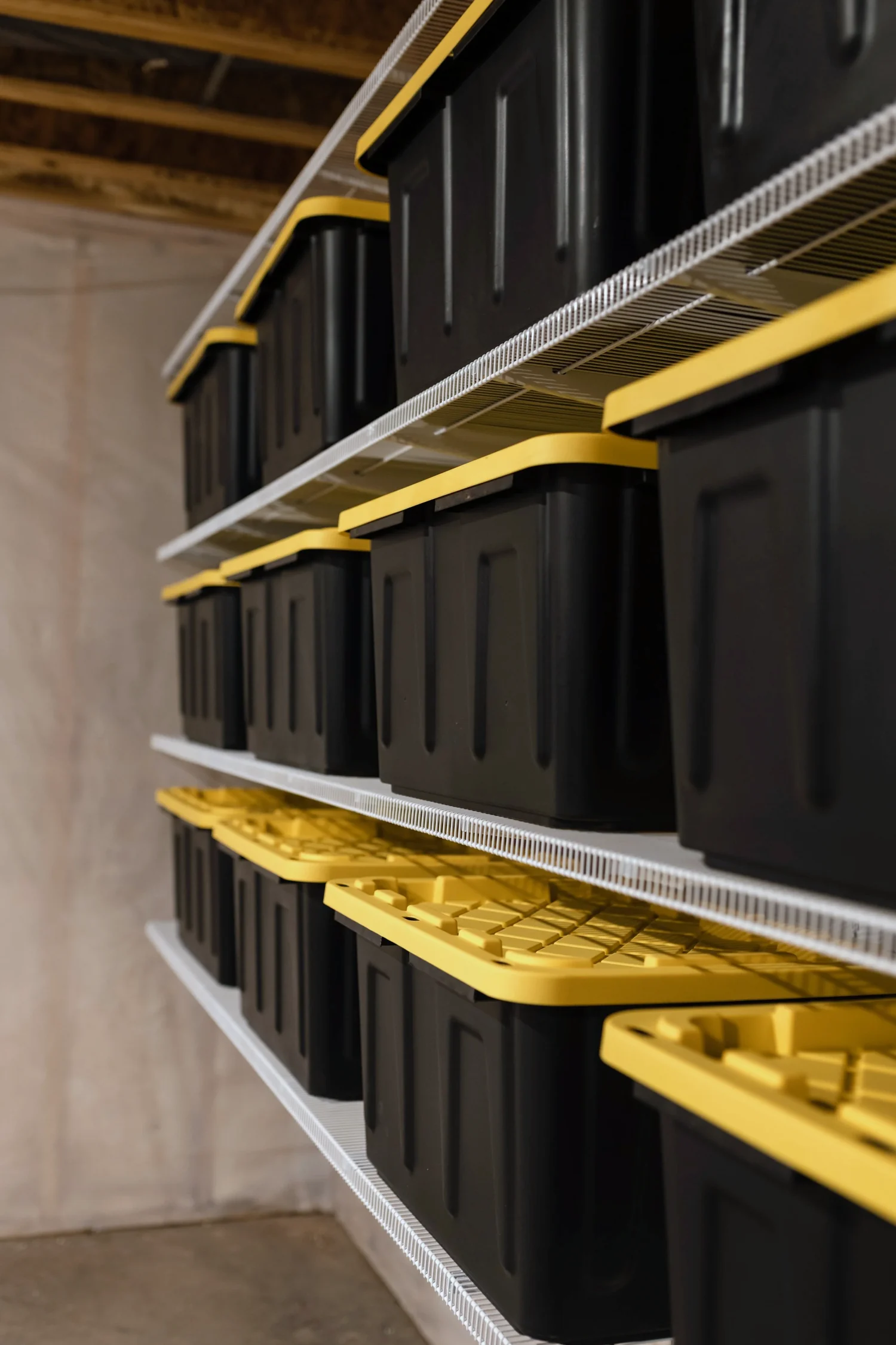 Angled view of storage bins on white wire shelves along a basement wall