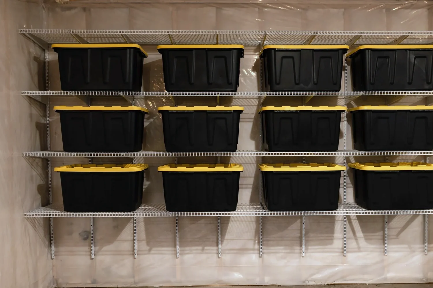 Storage bins in even rows on white wire shelves across a basement wall