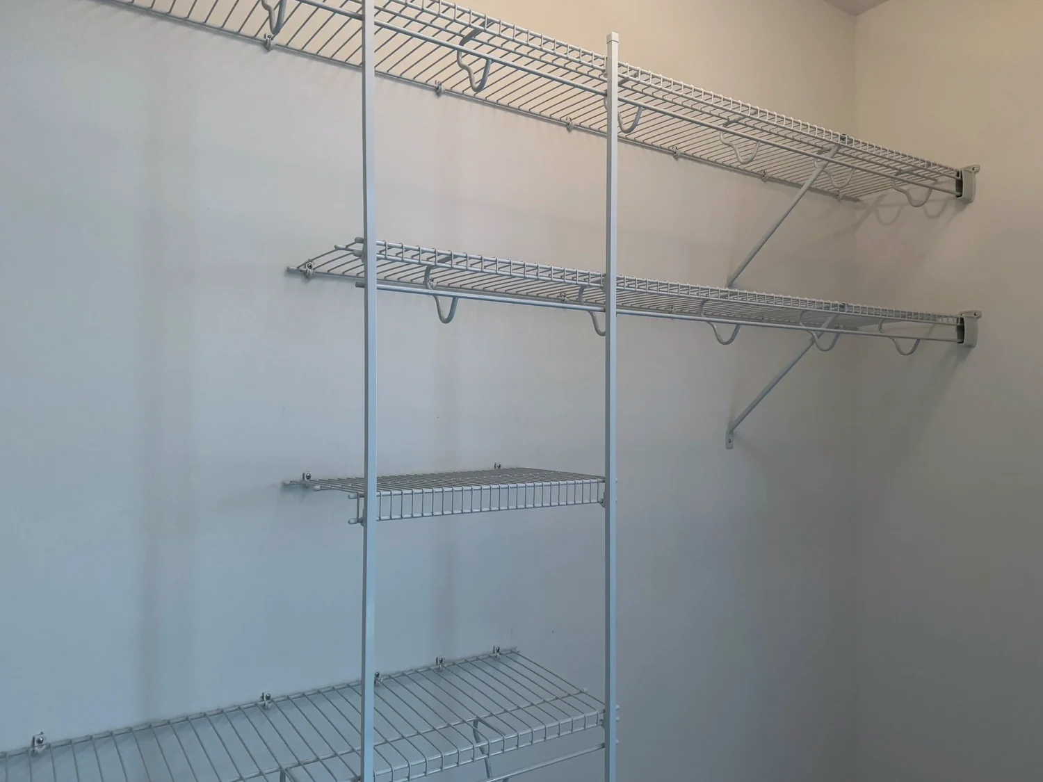 Wire shelves, hanging rods, and a column of short shelves on a closet wall
