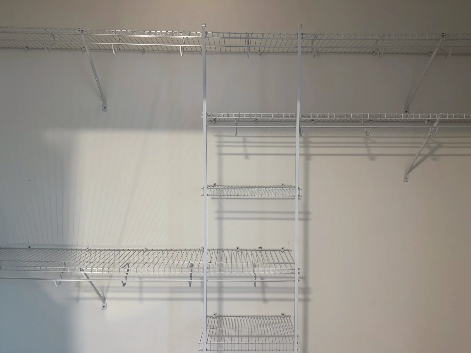 Long wire shelves with hanging rods and a center column of short shelves on a closet wall