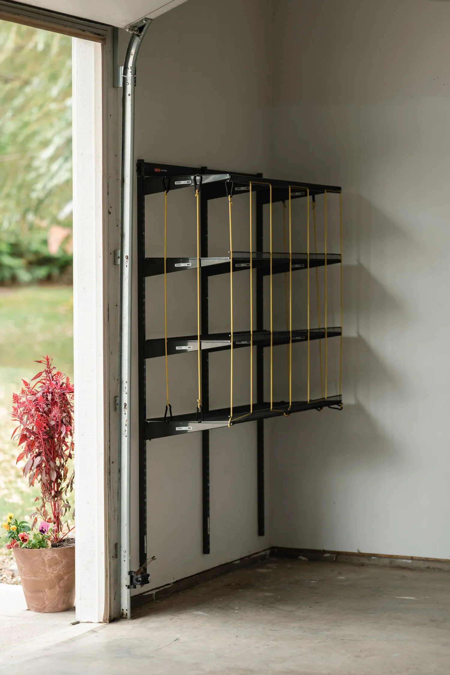 An empty ball rack on gunmetal wall rails in the corner of a garage