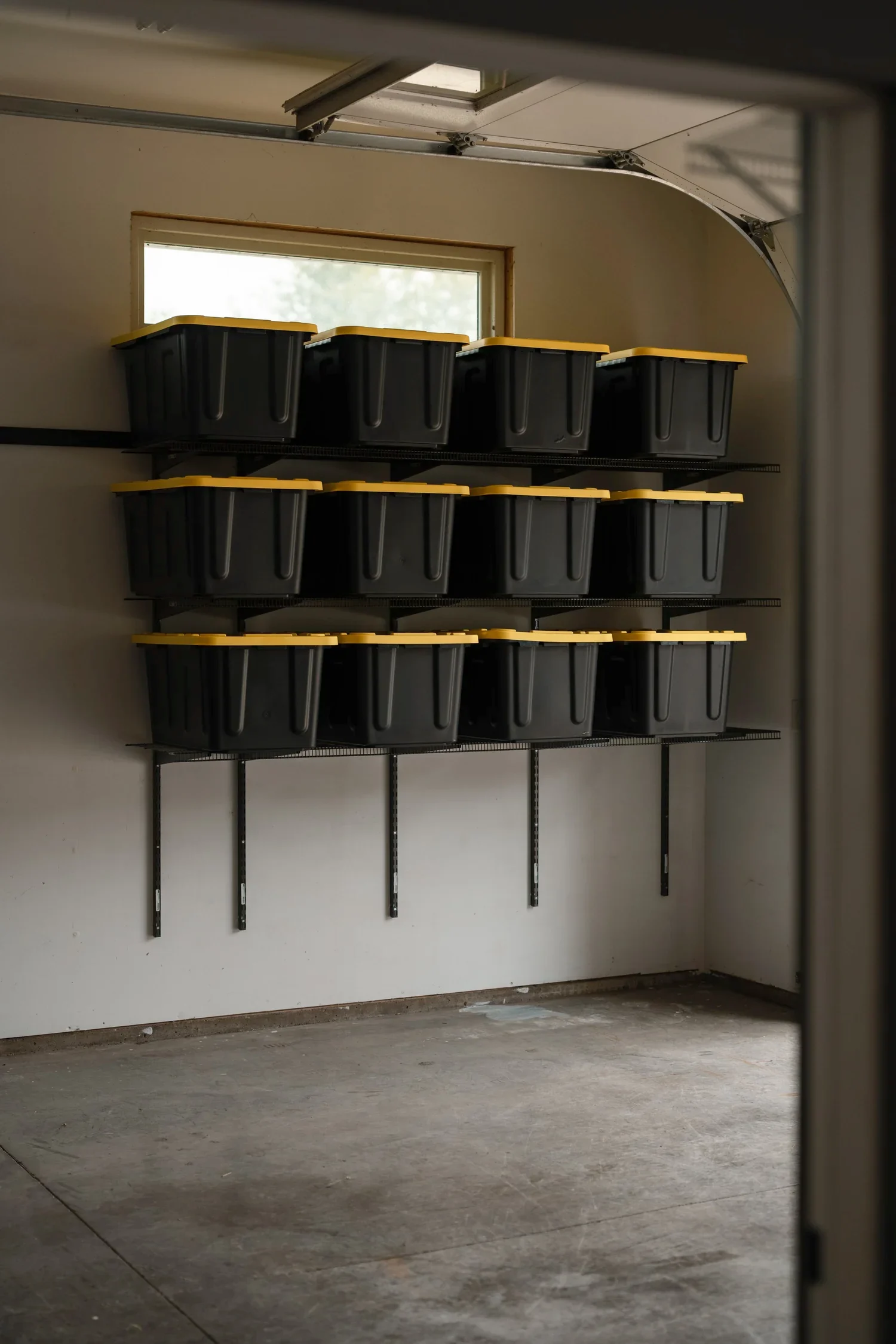 Black storage bins on gunmetal garage shelves, framed by the garage door jamb