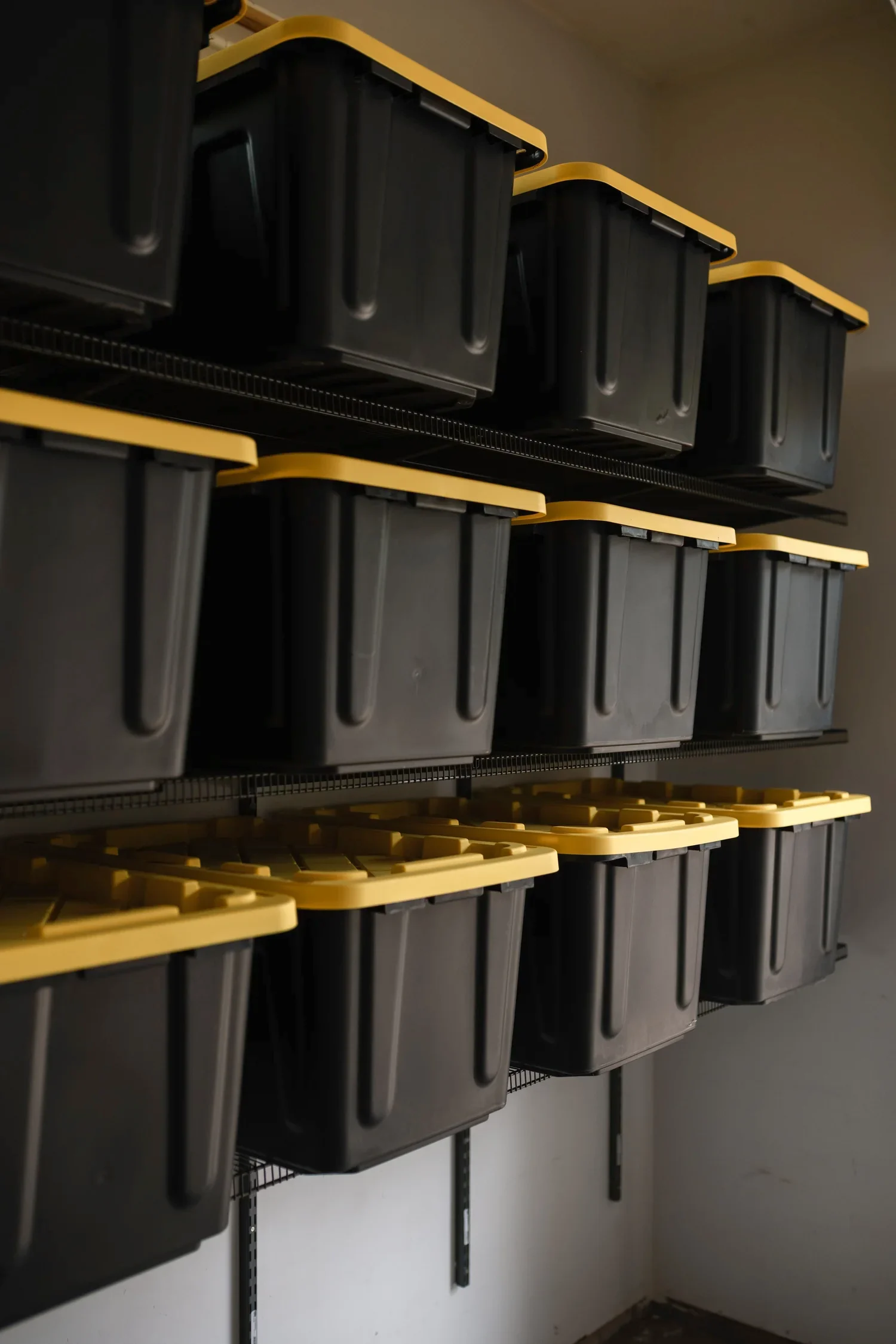 Low view of storage bins with yellow lids stacked on gunmetal garage shelves