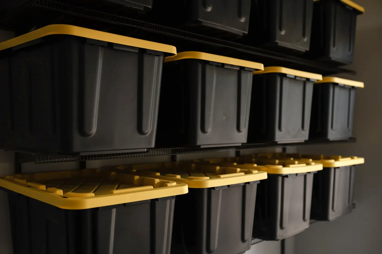 Angled close view of black storage bins resting on gunmetal wire shelves