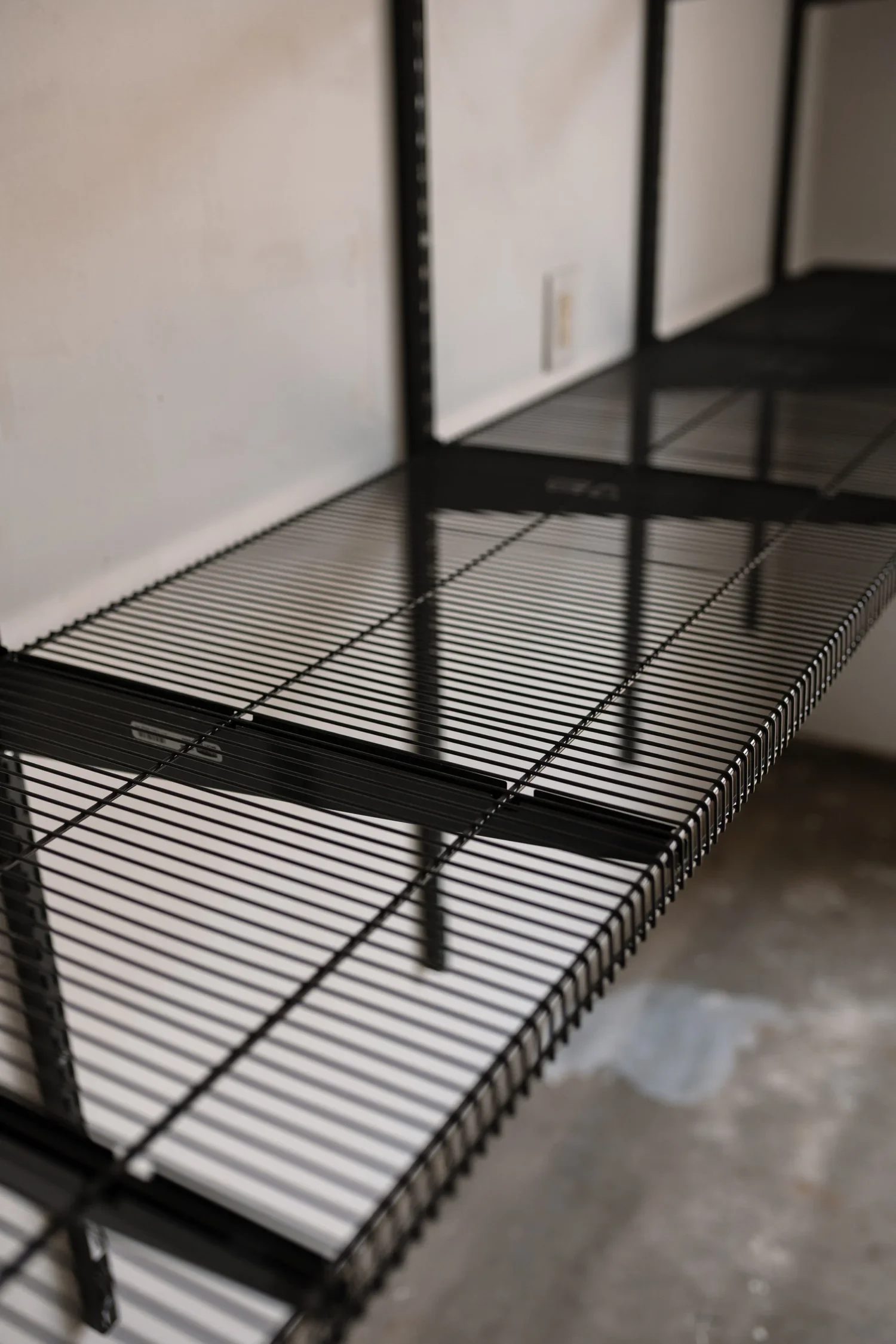 Close view of a gunmetal wire garage shelf on its brackets