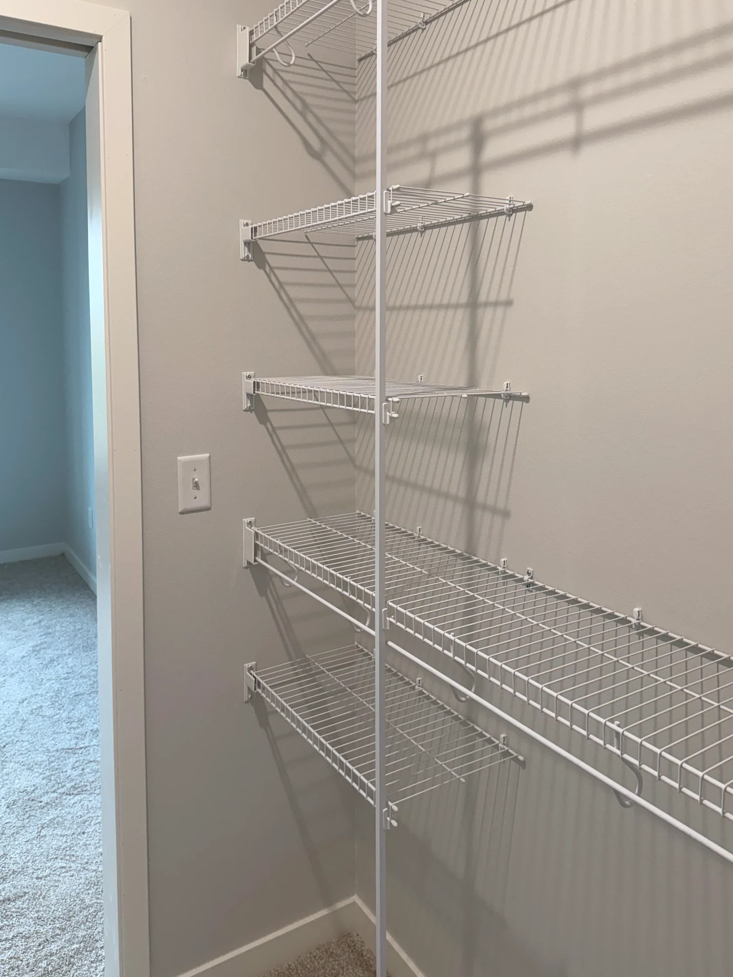 Wire shelves and a floor-to-ceiling support pole beside the doorway of a walk-in closet