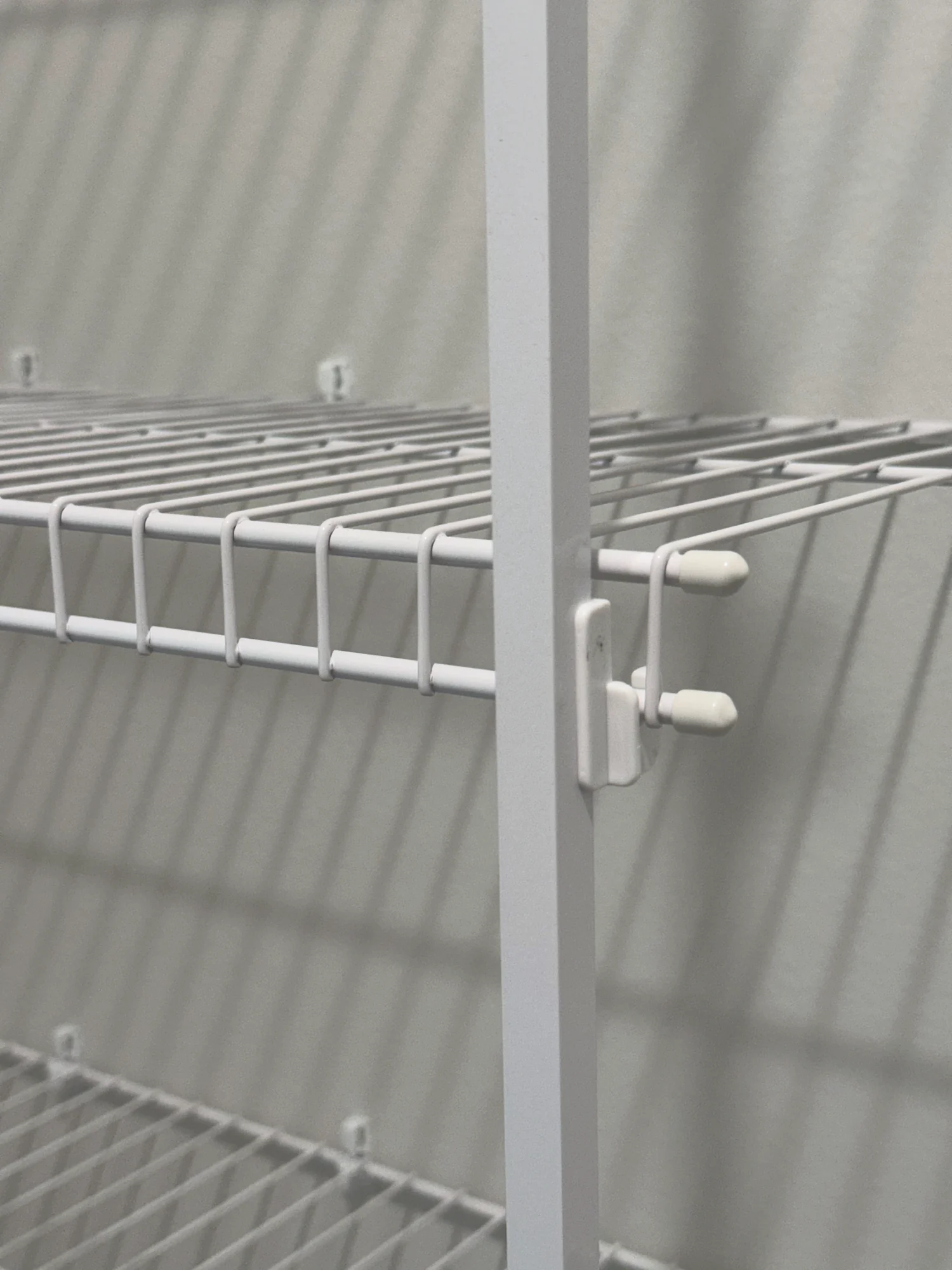 Close view of a wire shelf clipped to a white support pole