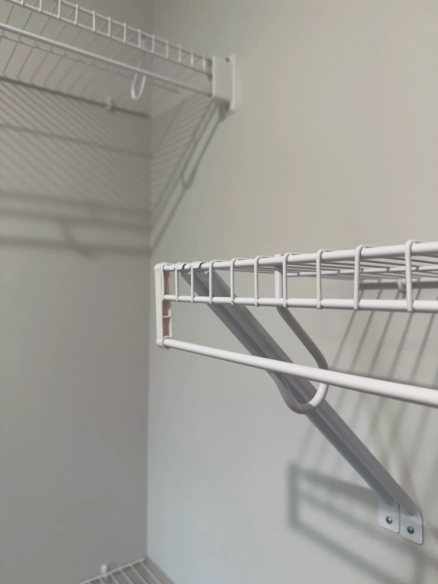 Close view of a wire shelf with a hanging rod and its diagonal wall brace