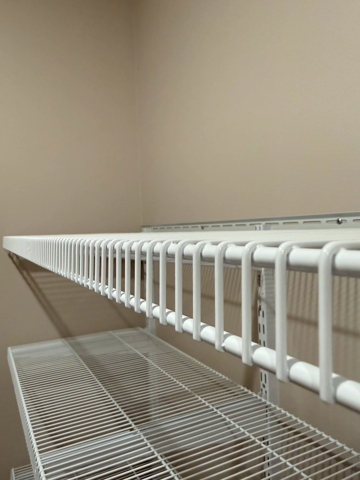 Close view along a white wire shelf with a hanging rod in a laundry room