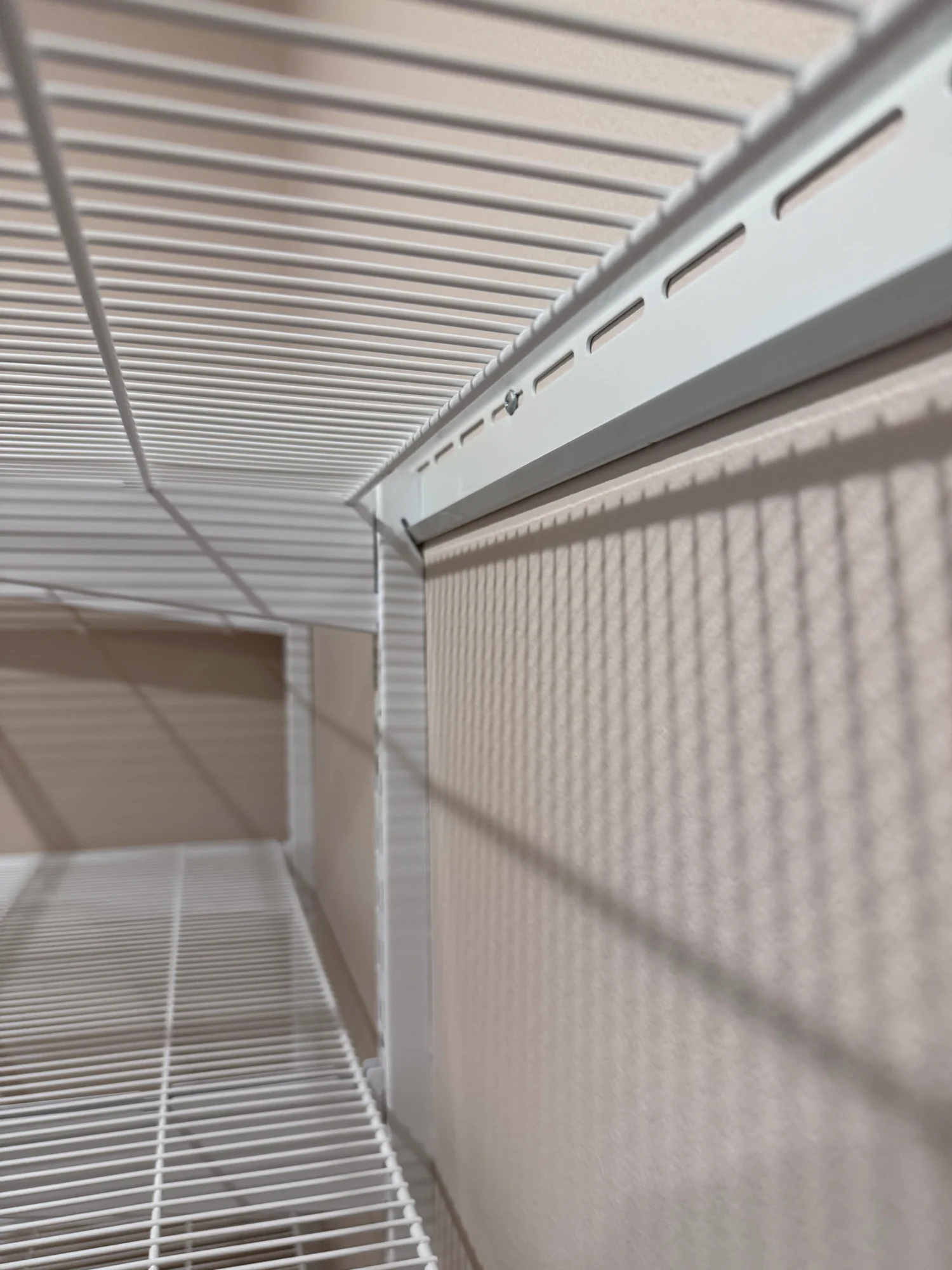 Looking along the underside of a white wire shelf mounted on wall standards