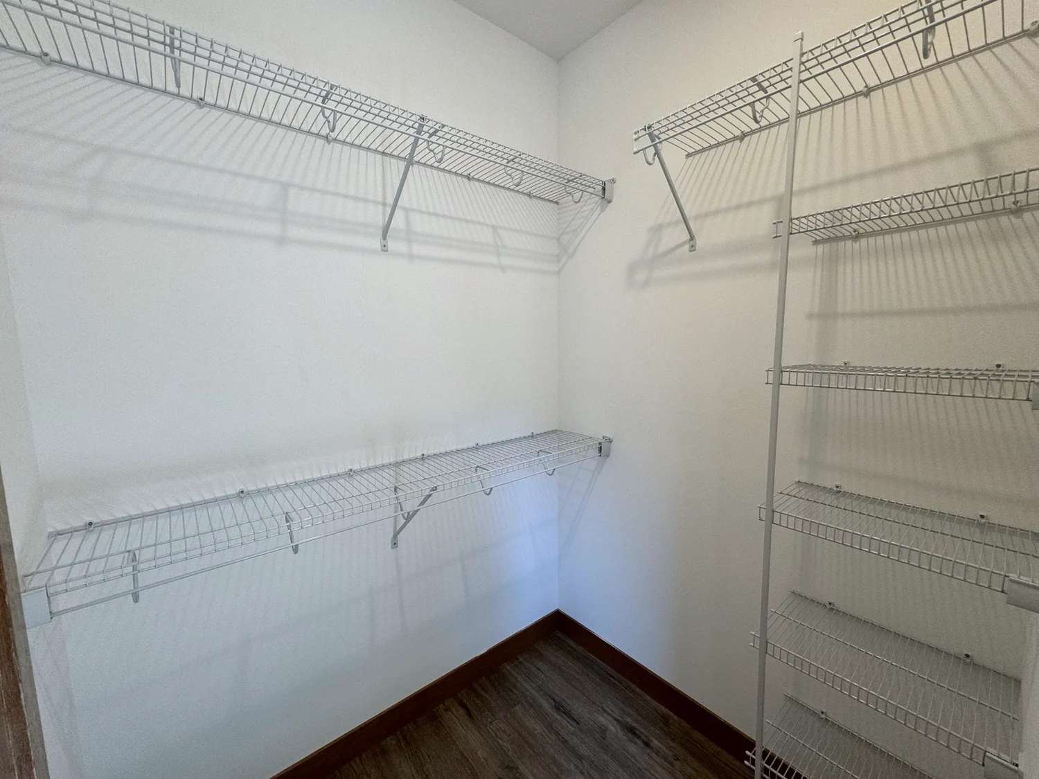Wire shelves with hanging rods and a tall shelf tower in an empty walk-in closet