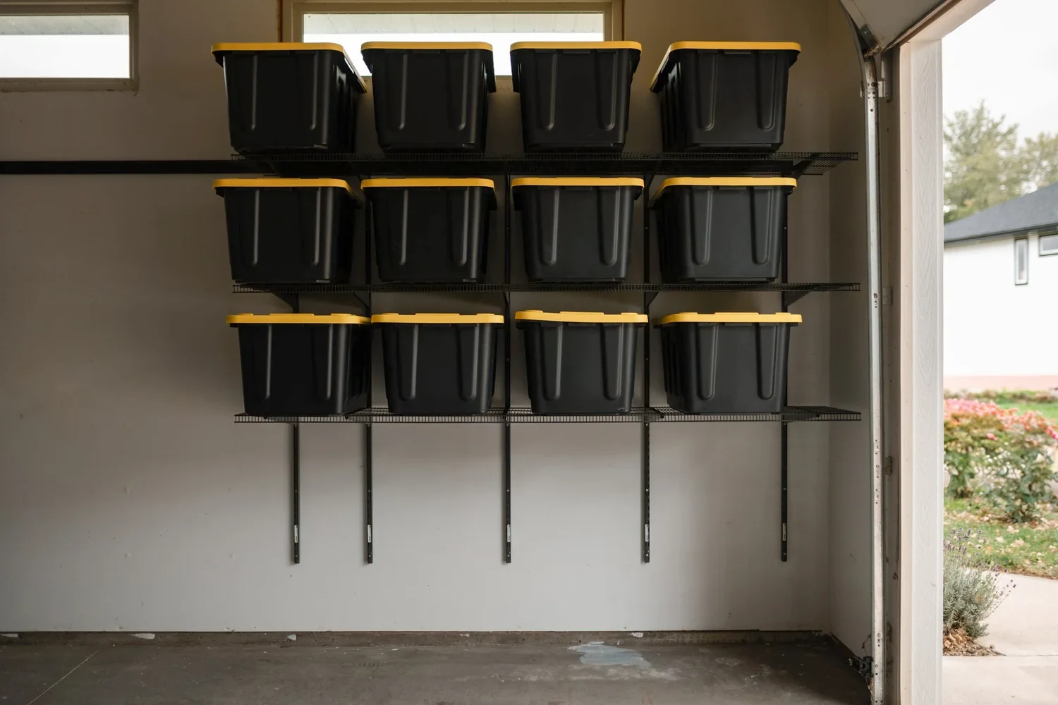 Twelve storage bins on three gunmetal garage shelves