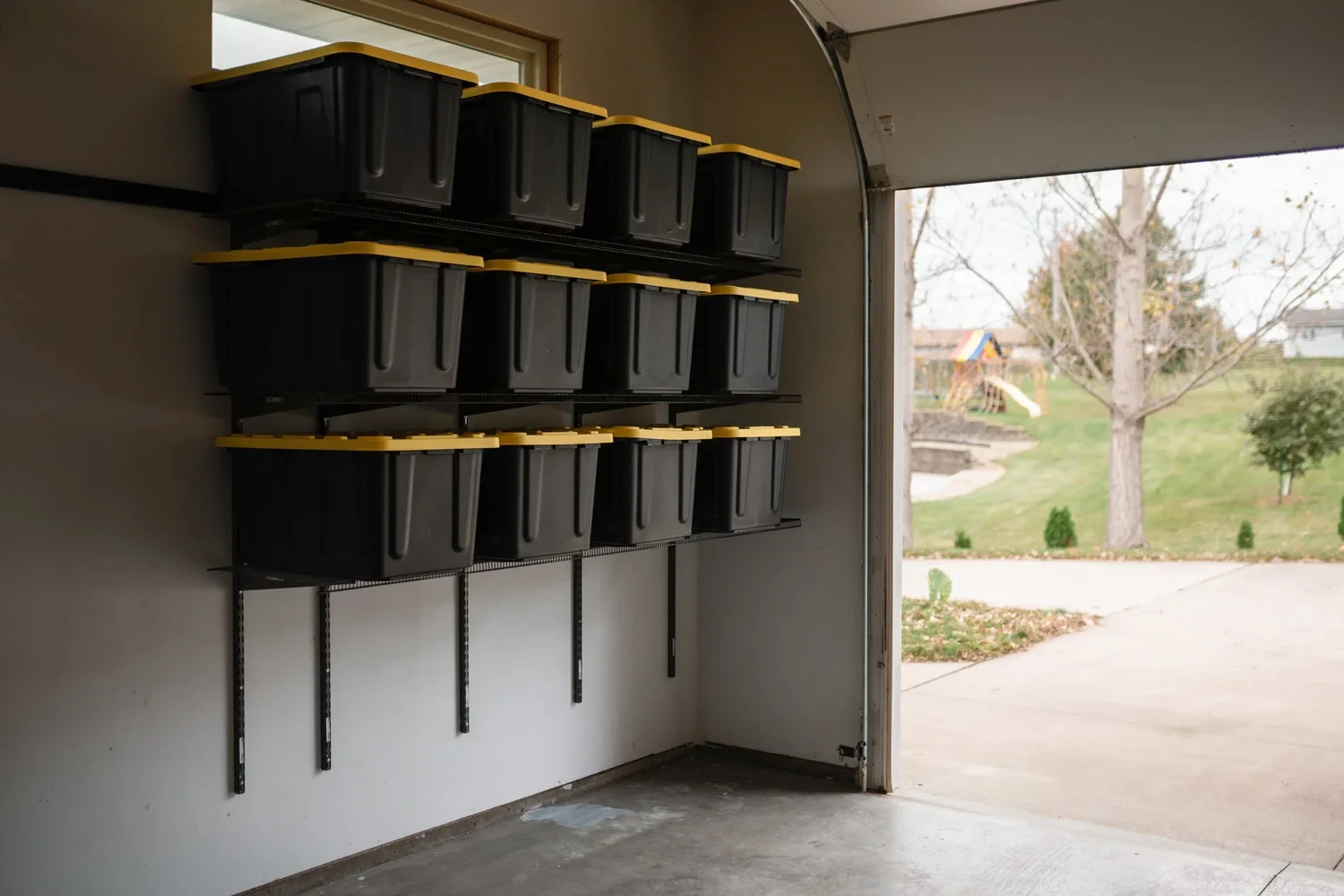 Storage bins on gunmetal garage shelves beside an open garage door