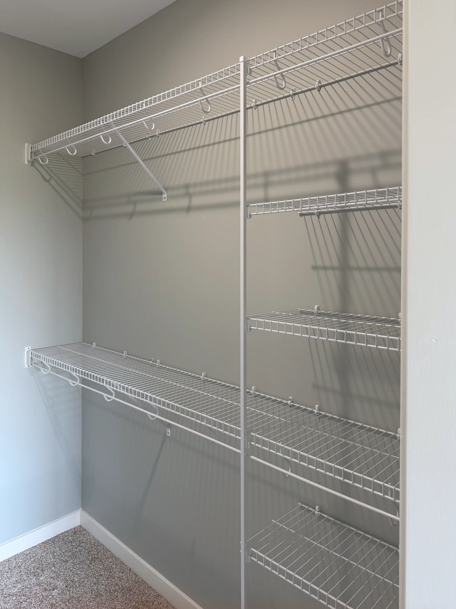 White wire shelving with hanging rods and a column of short shelves in a walk-in closet
