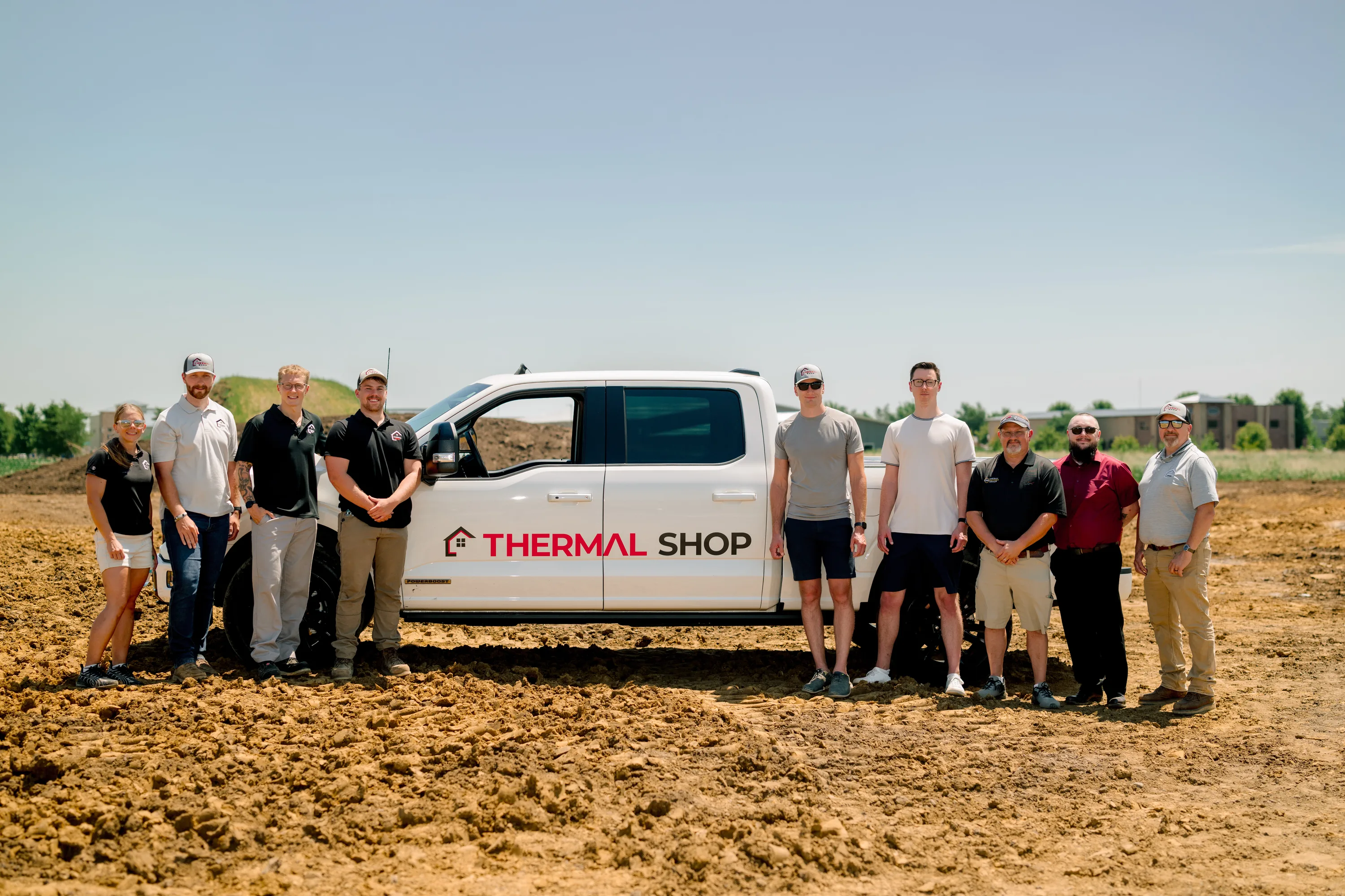 The Thermal Shop team standing in front of a white Thermal Shop pickup on a graded jobsite